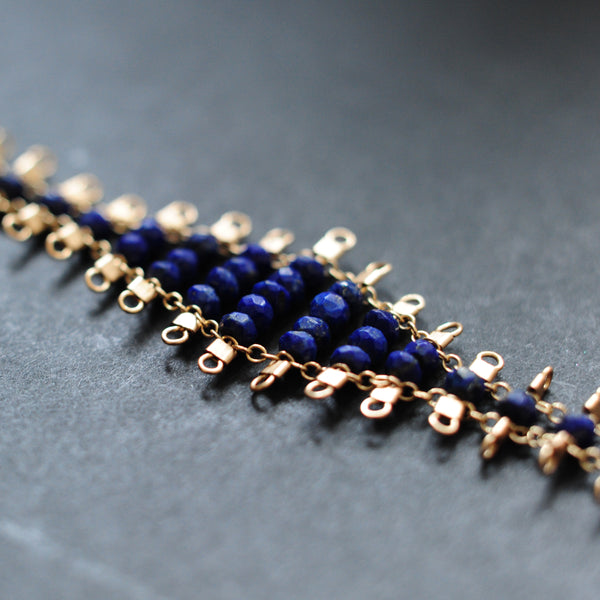 Juda bracelet, featuring faceted, navy blue, lapis lazuli beads suspended on 14k gold-fill wire and chain, finished with a lobster clasp.  Approximately 7 inches in length.