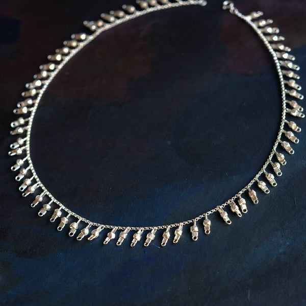 A sterling silver fringe-style necklace of silver faceted beads dangling off a silver chain all the way around.