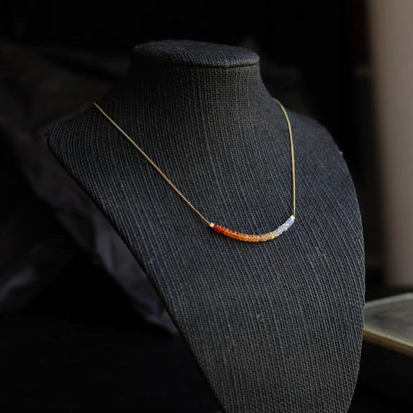 A thin, gold chain necklace strung with 2 inches of Mexican fire opal in milky to orange ombre tones.