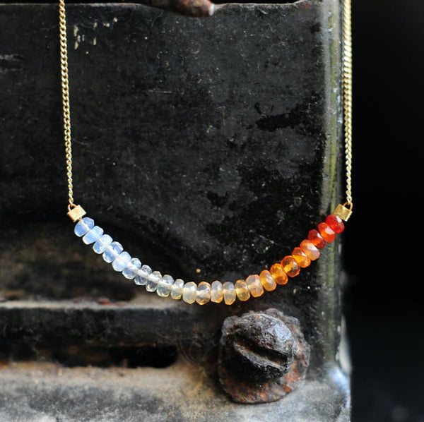 A thin, gold chain necklace strung with 2 inches of Mexican fire opal in milky to orange ombre tones..