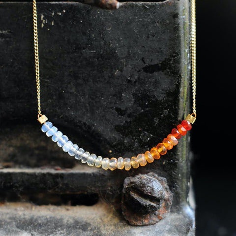 A thin, gold chain necklace strung with 2 inches of Mexican fire opal in milky to orange ombre tones..